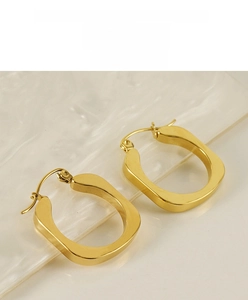 Macro shot of 18K gold-plated U-shaped steel earrings on a textured glass surface