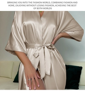 Détail de la texture d'un peignoir en satin de soie champagne avec ceinture et drapé fluide