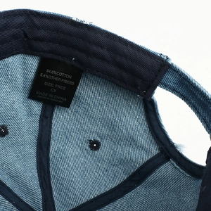 Detailed fabric label of denim baseball cap showing 94.6% cotton material and care instructions