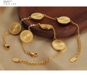 Detail of two gold-plated stainless steel bracelets with sunburst round pendants on satin