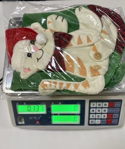 Detailed view of striped cat Christmas stocking being weighed on a digital scale at 0.137kg