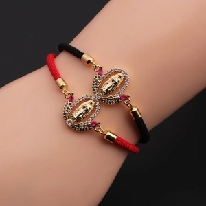 Close-up of adjustable braided bracelets with gold Virgin Mary pendants and crystals