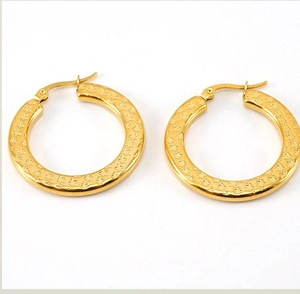 Detail of gold hoop earrings featuring embossed star patterns and secure snap closure