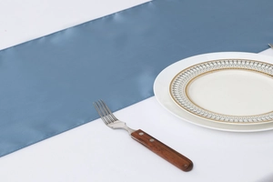 Detail view of a premium blue satin table runner with smooth glossy texture on a table