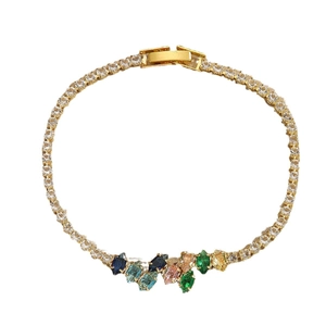 Minimalist gold bracelet with nine colorful leaf-shaped rhinestones on a white background