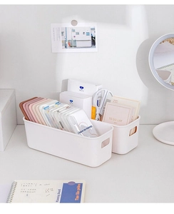 Close-up of matte white plastic storage bins with handles for desk drawer organization