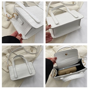Detail view of white crocodile pattern handbag with gold hardware and removable strap