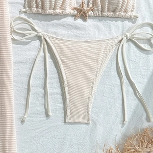 Close-up of cream textured bikini set featuring a golden starfish charm and tie-side details