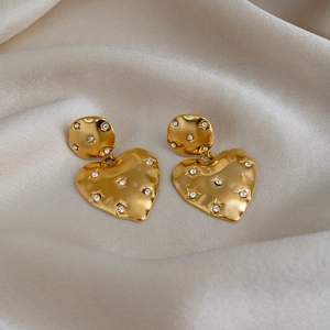 Detail of 18k gold heart earrings with sparkling star-set zircon stones on ripple texture