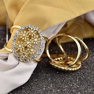 Close-up of golden hollow flower napkin rings with sparkling crystal embellishments