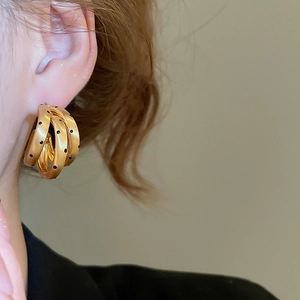 Dettaglio della modella che indossa orecchini a C placcati oro 18k con motivo a punti