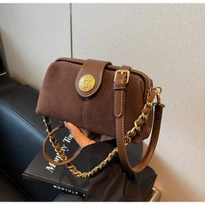 Close-up of brown matte suede doctor bag with gold chain and vintage embossed logo