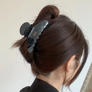 Detail of a chic black acetate shark hair clip with gold lettering on an elegant updo
