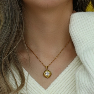 Close-up of gold square pendant with cable textured edge and clear zircon on chain
