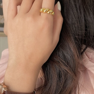 Close-up of a chunky golden twisted rope ring worn on a finger with a polished finish