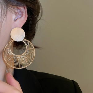 Detail of a large gold geometric earring with fine wire wrapping on a female model