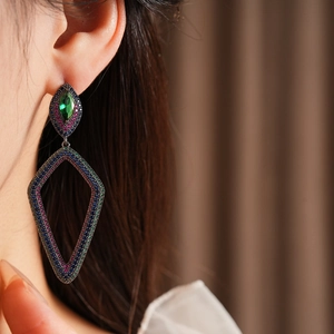 Close-up of vintage floral drop earrings with green and blue stones on model