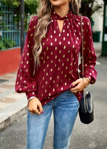 Close-up of wine red long-sleeve blouse with gold polka dots and hollow neckline