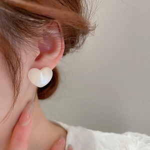 Close-up of heart-shaped mermaid pearl earrings worn for a luxury jewelry look