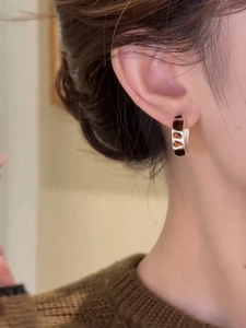 Close-up of a woman wearing retro silver and brown geometric enamel hoop earrings