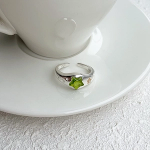 Close-up of S925 sterling silver ring with green star gemstone on a white ceramic saucer