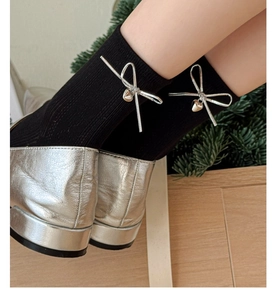 Détail de chaussettes mi-mollet noires avec nœud argenté et pendentif en cœur