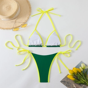 Flat lay of neon yellow and green bikini with beach accessories and yellow flowers