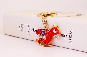 Detail of red rocking horse keychain with colorful rhinestones and gold plating