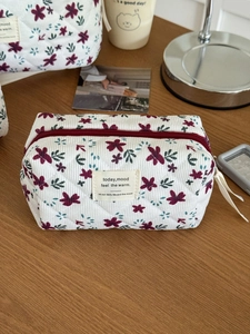 Macro detail of quilted corduroy cosmetic bag with red floral print and zipper