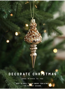 Detailed view of champagne beaded icicle ornament hanging on a Christmas tree branch