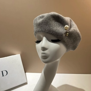 Close-up of a grey wool beret featuring elegant white pearls and golden bead accents