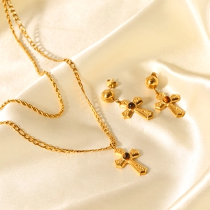Detailed view of gold cross jewelry set with brown tiger eye stones on silk fabric