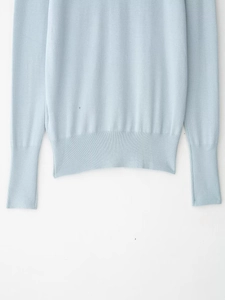 Detail of light blue knit sweater featuring ribbed cuffs and fine textured knitting pattern
