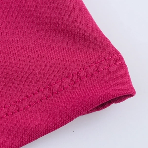 Vista macro del tessuto a maglia rosso rosa con cuciture sull'orlo ad ago doppio di qualità