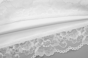 Gros plan sur la dentelle florale blanche avec bords festonnés et doublure assortie