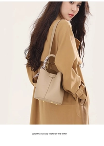 Detail view of beige leather bucket bag with silk scarf and elegant gold hardware