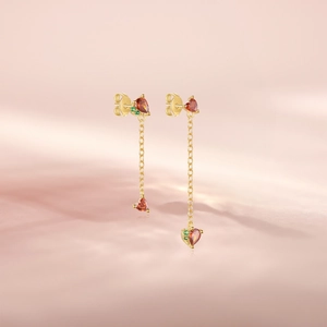 Detailed shot of gold tassel earrings with red heart crystals and green gems