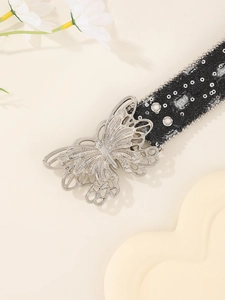 Detail of silver butterfly buckle on black canvas belt with sequins and rivets decoration