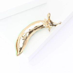 Detail view of the golden metal pepper brooch back with green enamel and pin fastener