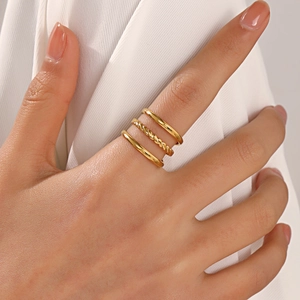 Three-piece stackable 18K gold plated stainless steel rings set for women on white fabric