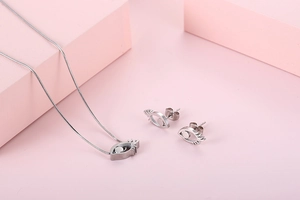 Detailed view of stylized eye necklace and earrings set on a minimal pink background