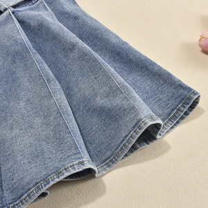 Detailaufnahme des plissierten Jeanskleid-Saums mit gelben Kontrastnähten und Textur