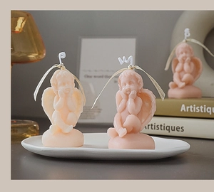 Artistic cherub angel scented candles in beige and pink displayed on a white plate
