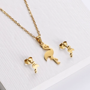 Golden flamingo pendant necklace and stud earrings jewelry set on a white wood background