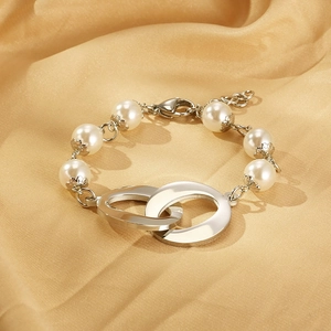 Detail of white pearls with interlocking silver rings on a golden silk fabric background