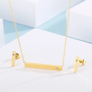 Detailed view of a gold bar necklace and earrings set with crystal inlay on a stand