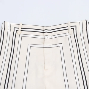 Detail der beigen weit geschnittenen Hose mit markanten schwarzen geometrischen Streifen