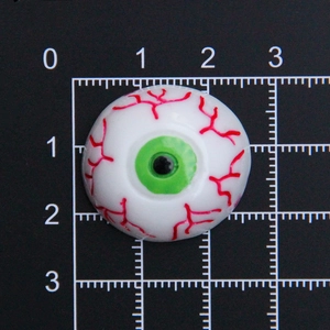 Accessoire œil en résine à dos plat avec veines rouges et iris vert sur règle