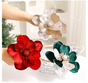Gros plan de trois fleurs de Noël en velours de 15 cm en rouge, or et vert pailleté