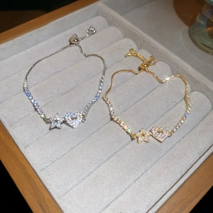 Close-up of adjustable zircon star and heart bracelets in silver and gold finishes